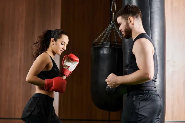 A male trainer near a brunette sportswoman in active wear boxing in a gym. — Stock Photo