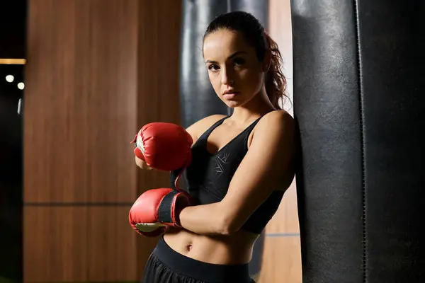 Brunette sportswoman in black top, red boxing gloves, boxing in gym. — Stock Photo