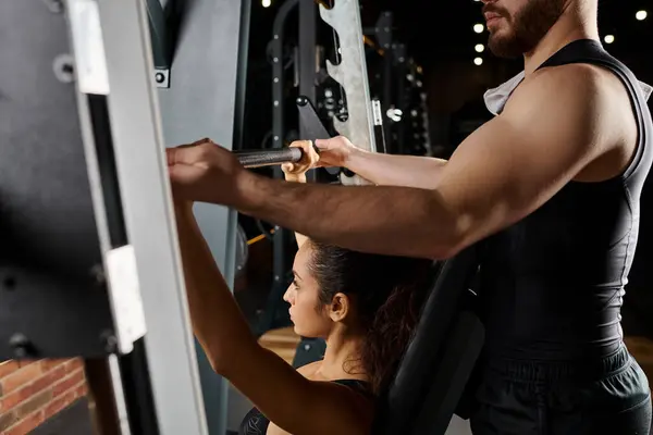 Мужской персональный тренер направляет брюнетку-спортсменку на тренировке в тренажерном зале, ориентированную на наращивание силы и выносливости. — стоковое фото
