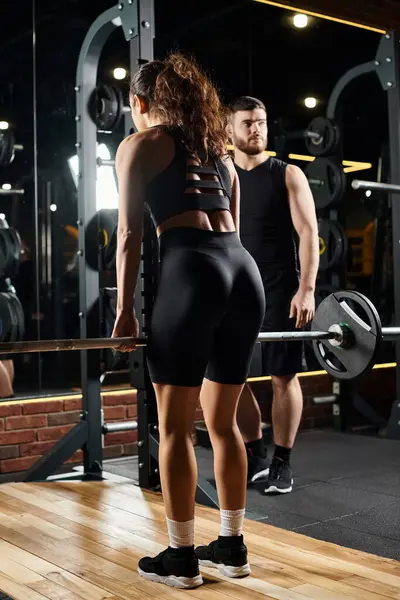 A male personal trainer guides a brunette sportswoman through exercises in a gym setting, focusing on strength and endurance. — Stock Photo