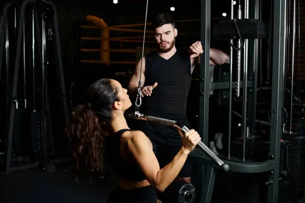 Тренер направляет брюнетку-спортсменку через упражнения в ярком тренажерном зале. — стоковое фото