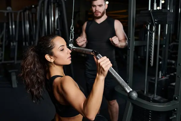 Un entraîneur masculin et une sportive brune sont vus travailler ensemble dans une salle de gym, concentrés et déterminés. — Photo de stock