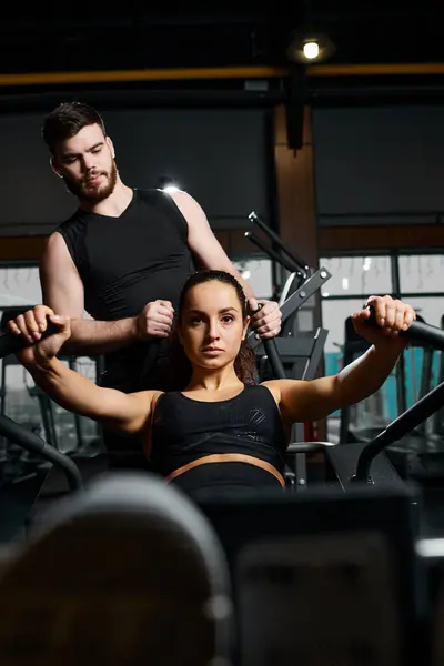 Un entraîneur masculin assiste une sportive brune avec des exercices dans une salle de gym. — Photo de stock