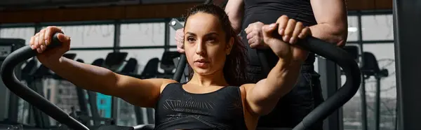 Eine Frau absolviert unter Anleitung eines männlichen Personal Trainers ein Workout an einem Gerät im Fitnessstudio. — Stockfoto