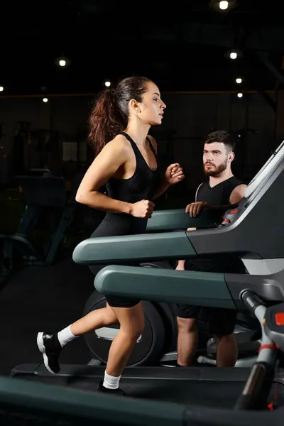 Тренер-мужчина мотивирует брюнетку-спортсменку бегать вместе на беговой дорожке в спортзале. — стоковое фото