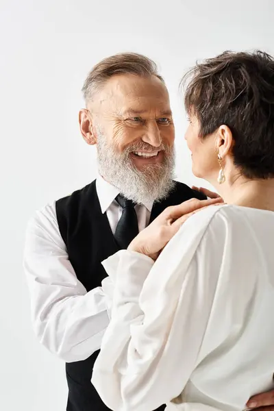 A middle-aged bride and groom in wedding attire standing closely together, celebrating their special day in a studio setting. — Stock Photo