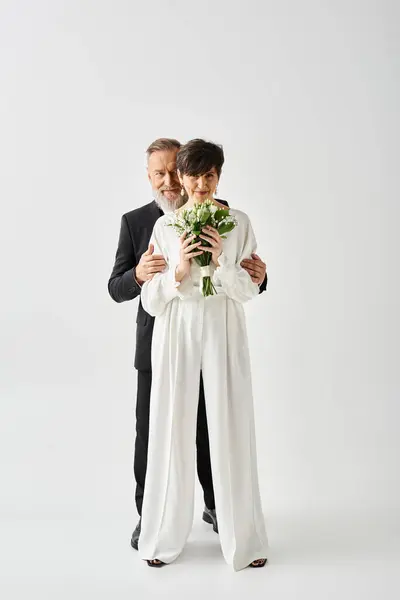 Braut und Bräutigam mittleren Alters im Brautkleid feiern ihren besonderen Tag gemeinsam im Studio-Ambiente. — Stockfoto