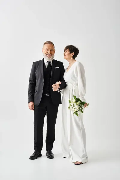 Braut und Bräutigam mittleren Alters in Hochzeitskleidung feiern ihren besonderen Tag im Studio. — Stockfoto