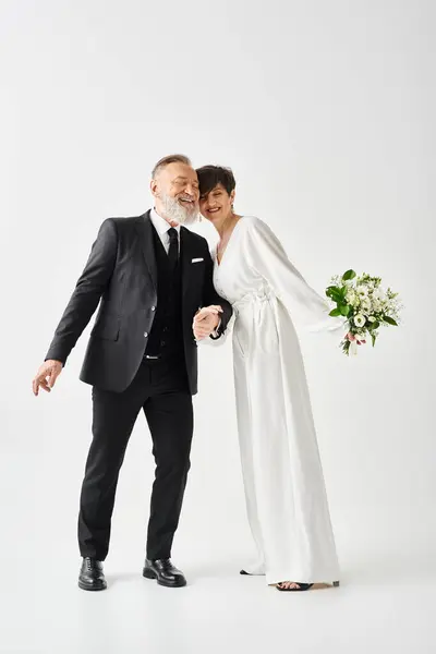 Middle-aged bride and groom, dressed in wedding gowns, strike a pose in a studio setting to capture their special day. — Stock Photo