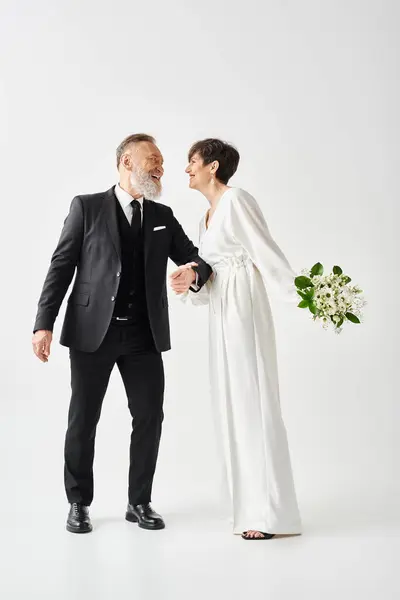 Mariée d'âge moyen et marié en costume de mariage noir et blanc célébrant leur journée spéciale dans un cadre de studio. — Photo de stock
