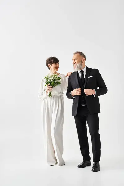 Braut und Bräutigam mittleren Alters in Hochzeitskleidung feiern ihren besonderen Tag im Studio-Ambiente. — Stockfoto