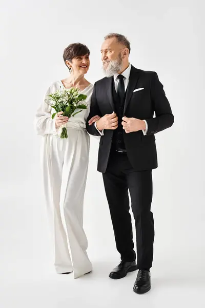 Una sposa e uno sposo di mezza età in elegante stand di abbigliamento formale uno accanto all'altro, celebrando il loro giorno speciale in un ambiente di studio. — Foto stock
