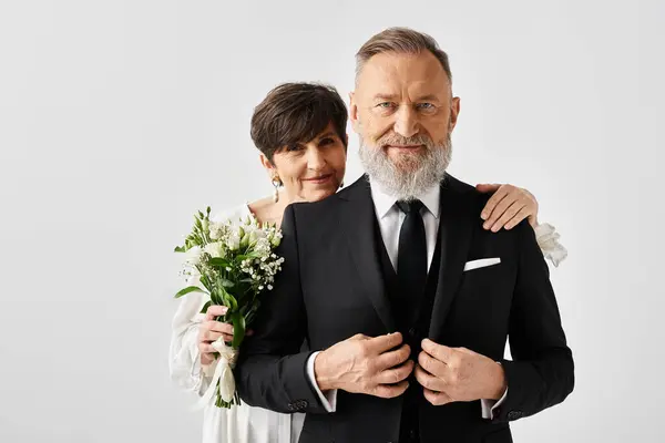 Middle-aged bride and groom in black and white wedding attire celebrating their special day in a studio setting. — Stock Photo