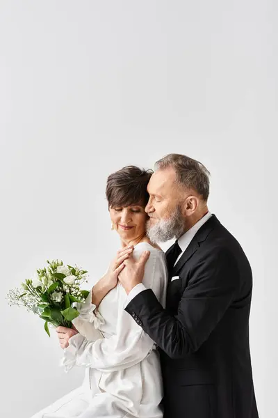 Una novia de mediana edad y el novio en vestidos de novia posan elegantemente en un estudio, capturando la esencia de su día especial. - foto de stock