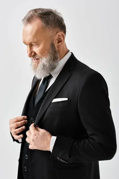 A middle-aged groom is elegantly adjusting his tie in a studio setting on his wedding day. — Stock Photo