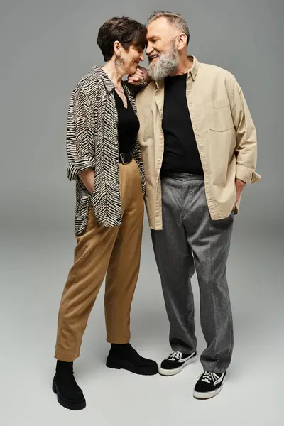 Un hombre y una mujer de mediana edad, vestidos con estilo, están uno al lado del otro en un entorno de estudio. - foto de stock