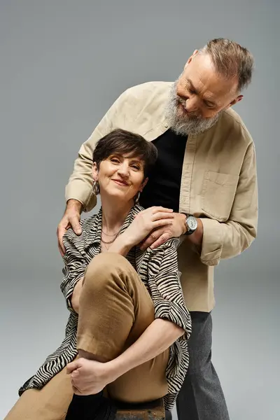 Un uomo di mezza età sostiene una donna sul retro di una sedia in un ambiente elegante studio, mettendo in mostra la fiducia e la partnership. — Foto stock