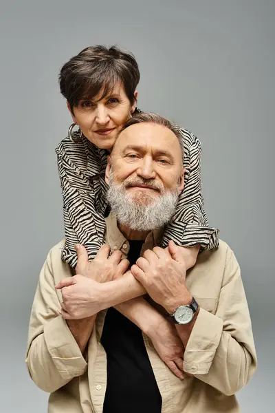 Ein Mann mittleren Alters in stilvoller Kleidung hebt eine Frau in einem Studio-Setting auf seine Schultern und zeigt Zuneigung und Stärke. — Stockfoto