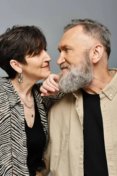 Un homme et une femme d'âge moyen se tiennent côte à côte dans une tenue élégante, exsudant sophistication et grâce dans un cadre de studio. — Photo de stock