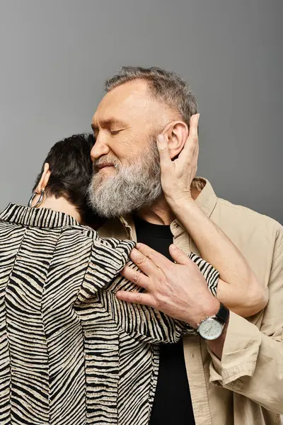 A middle aged couple in stylish attire embracing each other with joy in a studio setting. — Stock Photo