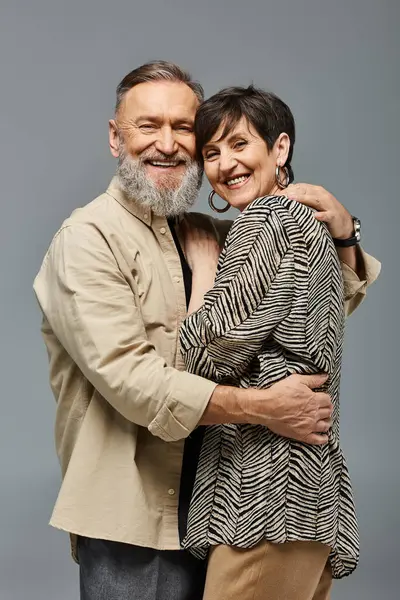 Una pareja de mediana edad con un atuendo elegante que comparte un cálido y sincero abrazo en un entorno de estudio, mostrando amor y conexión. - foto de stock