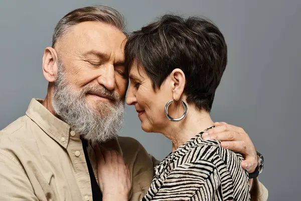 A middle-aged man and woman dressed in stylish attire embrace each other tenderly in a studio setting, showing love and connection. — Stock Photo