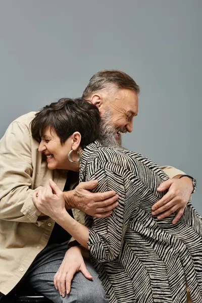 A middle-aged man lovingly hugs a woman from behind on the back of a chair in a stylish studio setting. — Stock Photo