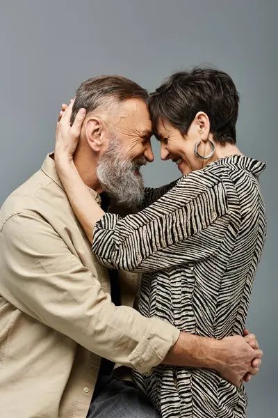 Un couple d'âge moyen en tenue élégante partageant un câlin chaleureux et intime dans un cadre de studio. — Photo de stock