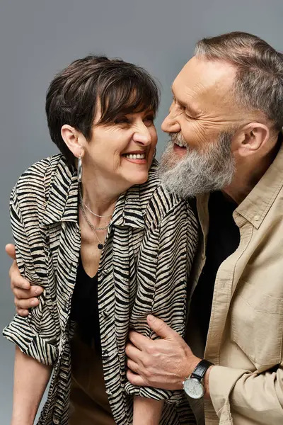 Un homme et une femme d'âge moyen vêtus élégamment, se souriant chaleureusement dans un décor de studio. — Photo de stock