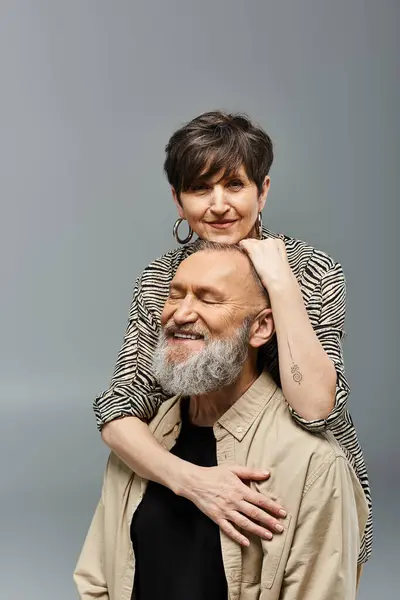 Un homme d'âge moyen tient une femme sur le dos dans un cadre élégant de studio, montrant la confiance, le soutien et la connexion. — Photo de stock