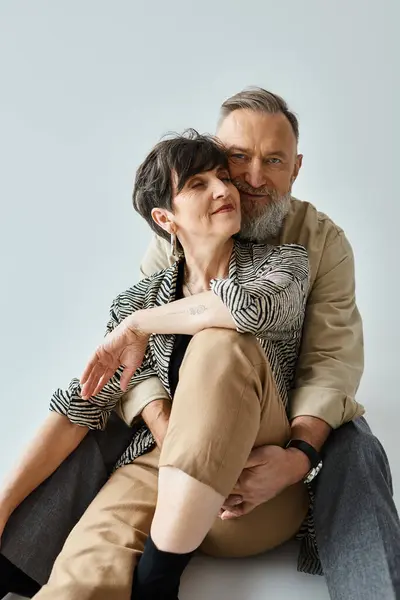 Stylish middle-aged couple seated closely, exuding charm and sophistication in a studio setting. — Stock Photo