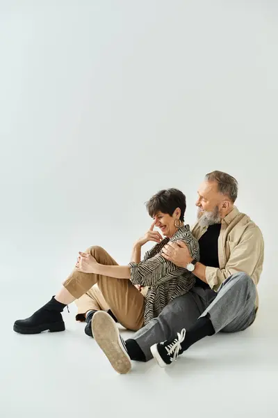 Um casal de meia-idade em trajes elegantes sentados juntos em um ambiente de estúdio, exalando sofisticação e unidade. — Fotografia de Stock