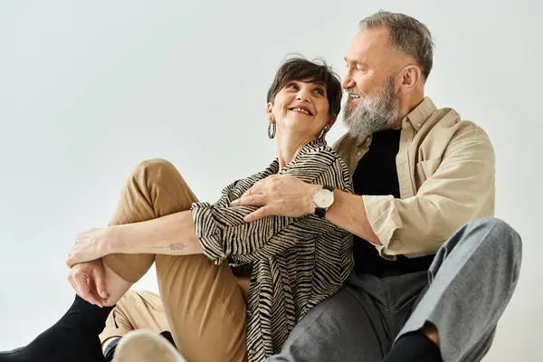 Um casal de meia-idade em trajes elegantes sentados juntos no chão em um ambiente de estúdio, compartilhando um momento de paz e conexão. — Fotografia de Stock