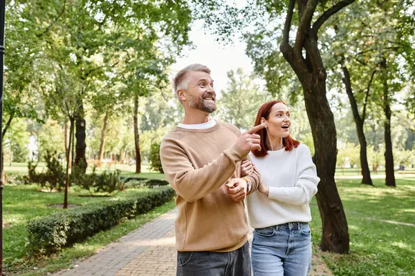 A couple, casually dressed, enjoy a leisurely walk through a scenic park. — Photo de stock
