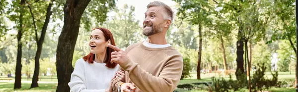 A loving adult couple in casual attire walking through a peaceful park. — Stock Photo