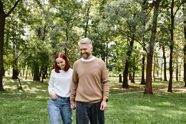 Adult couple in casual attire taking a leisurely walk through a serene park. — Stock Photo