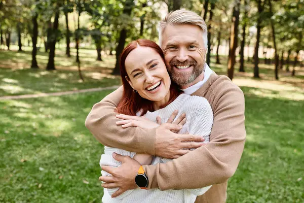 A man tenderly hugs a woman in a serene park setting. — Stock Photo