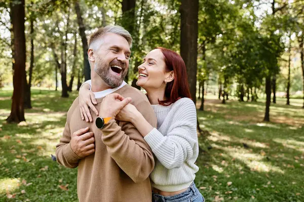 A man tenderly holds a woman in a park setting. — Stock Photo