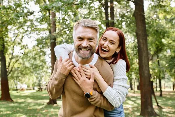 Man holding woman in loving embrace in a serene park setting. — Stock Photo