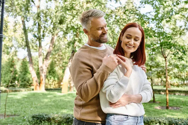 A loving couple in casual attire stands together in a park. — Stock Photo