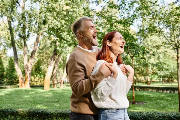 A man and a woman laughing together in a park. — Stock Photo