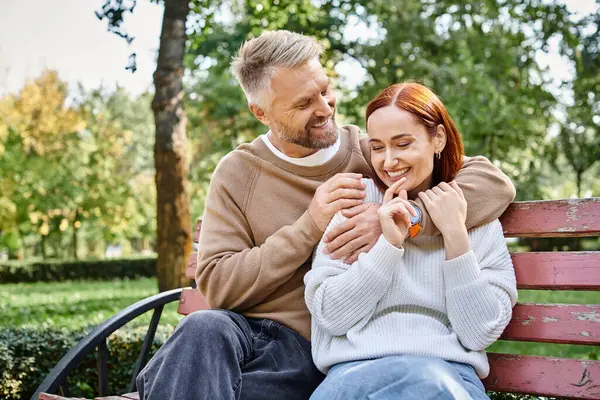 Couple aimant adulte en tenue décontractée se relaxant sur un banc de parc. — Photo de stock