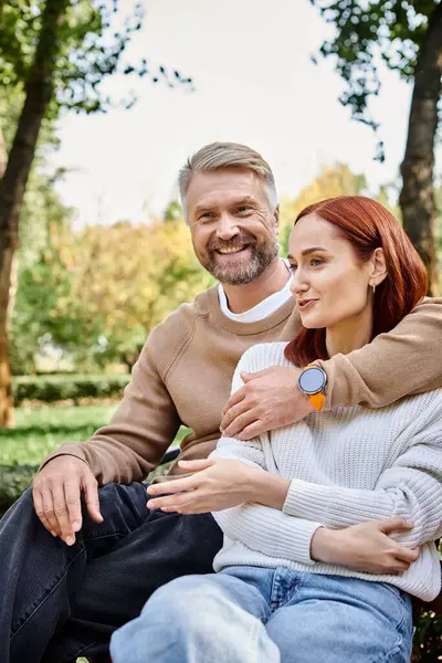 A man and a woman in casual attire sit on a park bench, enjoying a peaceful moment together. — Stock Photo