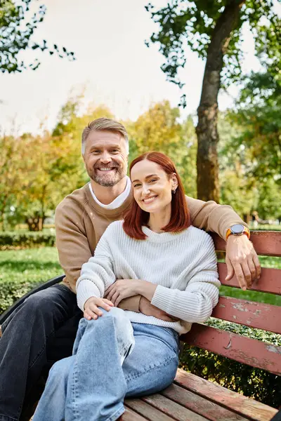 Adult couple in casual attire enjoying a peaceful moment on a park bench. — Stock Photo