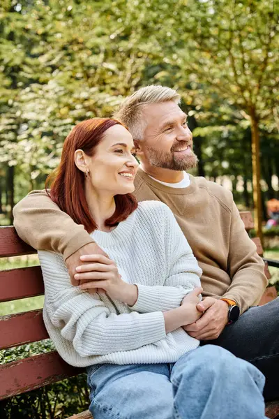 A man and woman enjoy a peaceful moment on a bench in the park. — Stock Photo