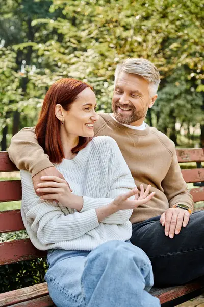 Un homme et une femme en tenue décontractée s'assoient paisiblement sur un banc de parc. — Photo de stock
