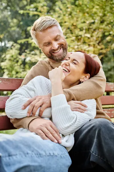Un homme et une femme tranquillement assis ensemble sur un banc tranquille dans un parc. — Photo de stock