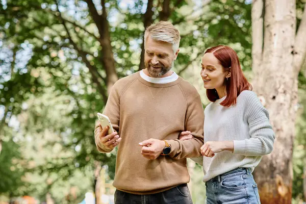 An adult man and woman in casual attire stand side by side in a park. — Stock Photo