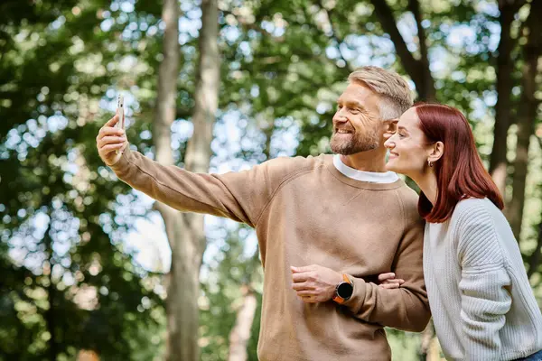 Un homme et une femme capturent un moment dans le parc avec un téléphone portable. — Photo de stock