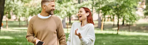 A man and a woman enjoy a leisurely stroll in a lush park setting. — Stock Photo